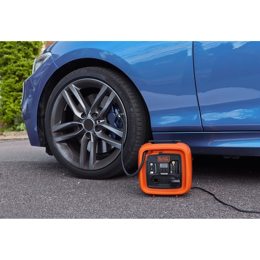 BLACKDECKER ASI400 portable air compressor inflating car tire, orange casing, automotive use.