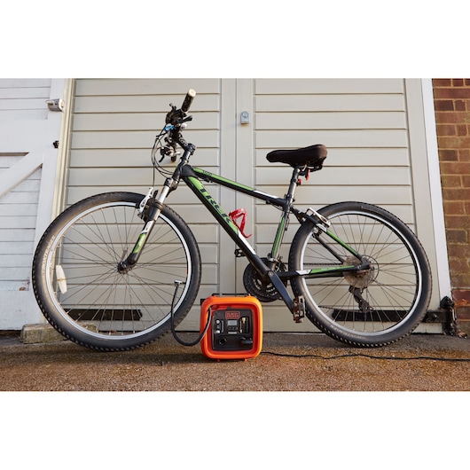 BLACKDECKER ASI400 portable air compressor next to a bicycle outdoors, front angle.