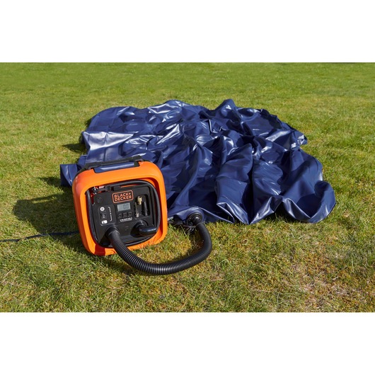 BLACKDECKER ASI400 portable air compressor next to a deflated blue inflatable, on grass outdoors.