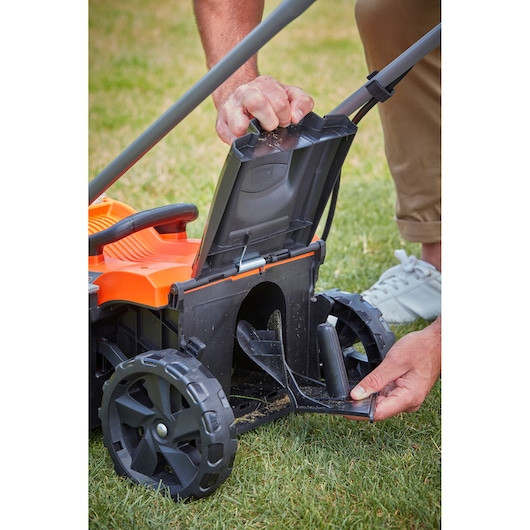 BLACKDECKER BCMW33182L2 lawn mower close-up showing rear discharge area with open flap on grass.