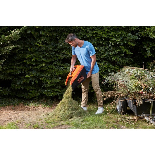 Photo of BLACKDECKER BCMW33184L2 lawn mower grass box being emptied outdoors.