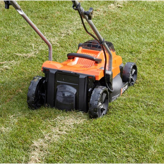 BLACKDECKER BCMW33184L2 orange cordless lawn mower on grass, rear view, showing wheels and handles.