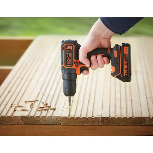BLACKDECKER BDCD18K cordless drill driving a screw into wooden planks, close-up side angle.