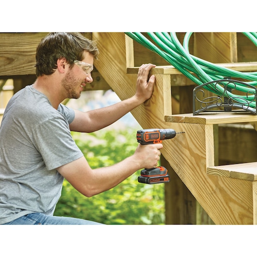 Photo of BLACKDECKER BDCDC18BAFC cordless drill used on wooden stairs outdoors.