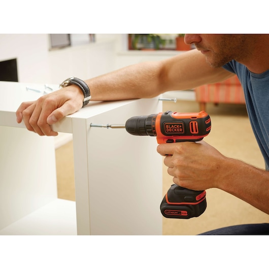 Photo of BLACKDECKER BDCDD12 cordless drill used to assemble white furniture indoors.