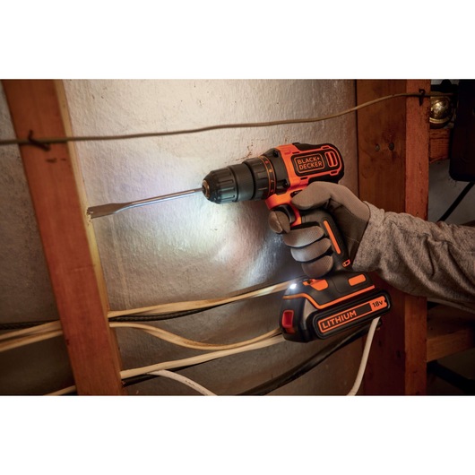 BLACK+DECKER BDCDD186B cordless drill driver in use, drilling wood, visible 18V lithium battery.