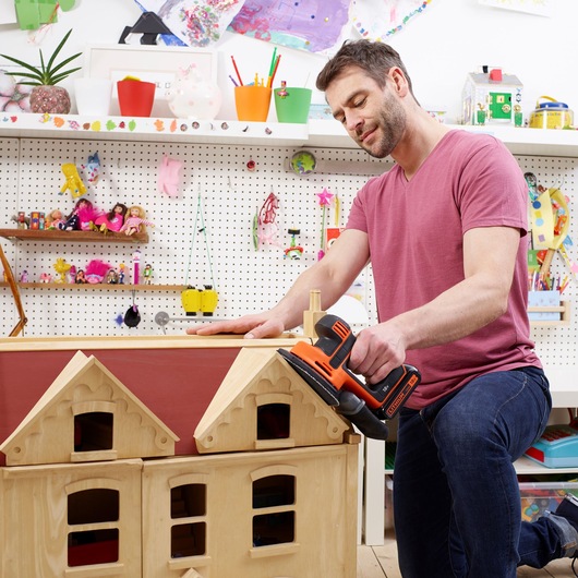 Photo of BLACKDECKER BDCDS18N sander used on wooden dollhouse roof in craft room setting.