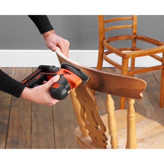 BLACKDECKER BDCDS18 cordless sander used on wooden chair, close-up angle.