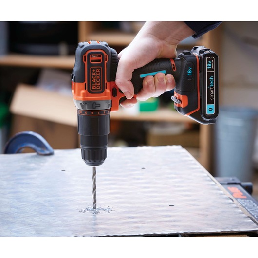 Photo of BLACK+DECKER BDCHD18KST cordless drill in use, drilling into metal sheet
