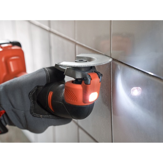 BLACKDECKER BDCOS18D1K cordless oscillating tool with LED light, close-up in use on wall tiles.