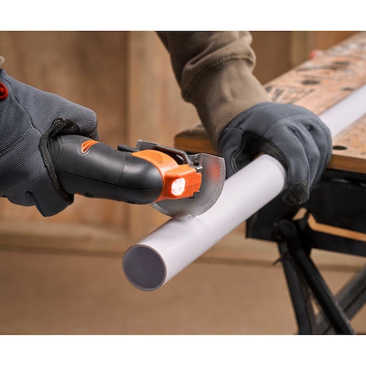 BLACKDECKER BDCOS18D1K compact saw cutting white PVC pipe, detailed action view, worker wearing gloves.