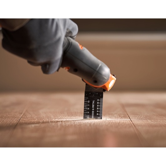 BLACKDECKER BDCOS18D1K oscillating tool used on wooden floor, close-up view.
