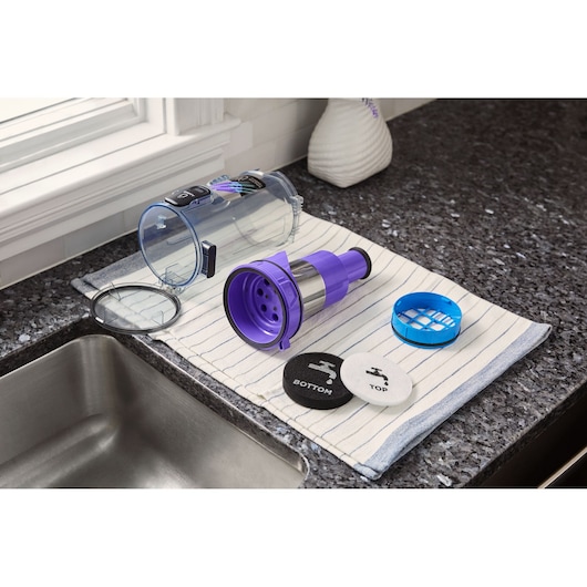 BLACKDECKER BHFEA640WG vacuum canister, filter components, and covers arranged on striped towel next to kitchen sink.