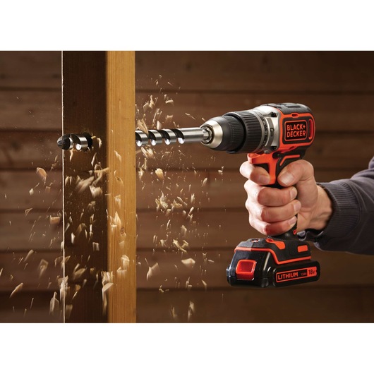 BLACKDECKER BL188KB cordless drill being used to drill through wood with wood shavings flying.