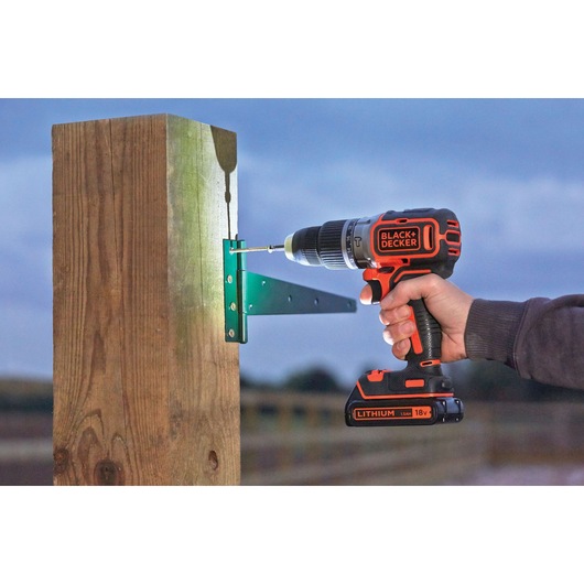 Photo of BLACK+DECKER BL188KB cordless drill driving screw into metal bracket on wooden post outdoors.
