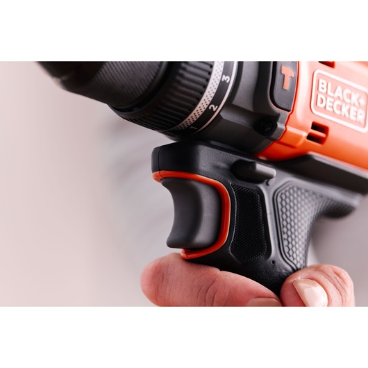 Close-up side view of BLACK+DECKER BLD683D1 drill grip and trigger held by a hand, showing textured black and orange handle.