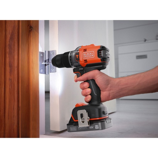 BLACK+DECKER BLD683XN cordless drill being used to install a screw in a door hinge, close-up side view.