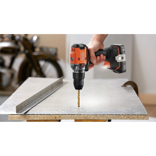 BLACK+DECKER cordless drill BLD683XN in use drilling into a sheet of metal on a workbench.