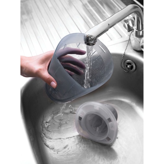 BLACKDECKER DV1415EL vacuum dust container being rinsed under tap water in a metal sink.