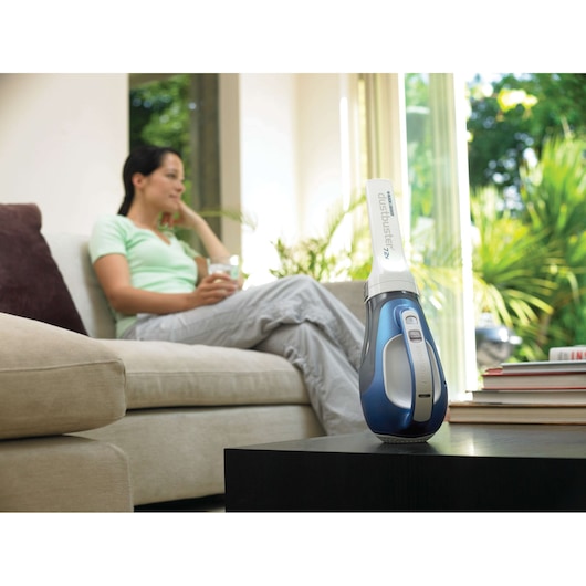 BLACKDECKER DV7210N handheld vacuum with white and blue design on a black table in a modern living room.