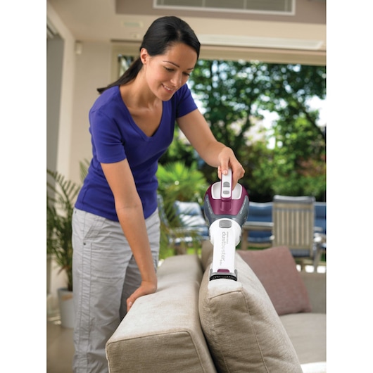 BLACKDECKER DV9610ECN handheld vacuum cleaning beige sofa in living room.