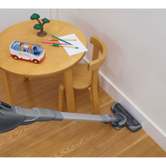BLACKDECKER FEJ520JFS stick vacuum cleaning hardwood floor near a child's table, angled side view.