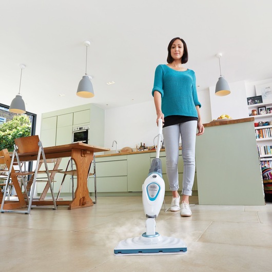 BLACKDECKER FSM1605 steam mop in use on kitchen floor, photography showing product cleaning action.