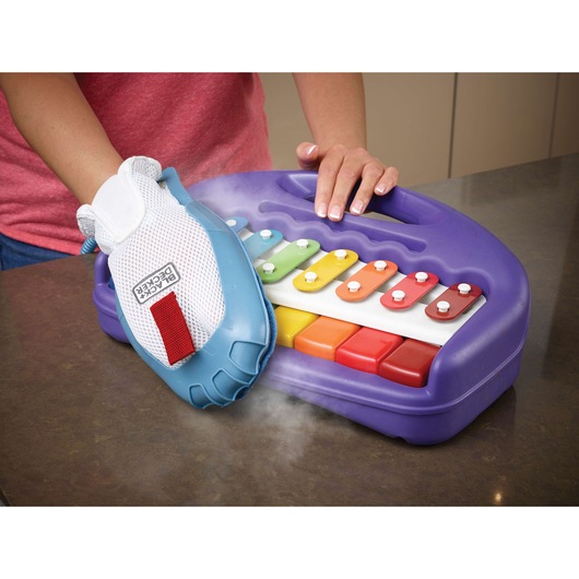 BLACKDECKER FSMH13101SM steam glove cleaning a purple toy xylophone with colorful keys on tabletop.