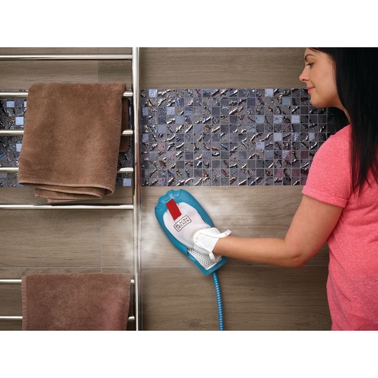 BLACK+DECKER FSMH13101SM handheld steam cleaner in use, cleaning mosaic tile wall near towel rack.