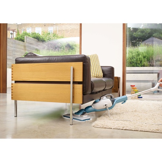 BLACKDECKER FSMH13101SM steam mop cleaning under brown wooden sofa in modern living room, side angle.