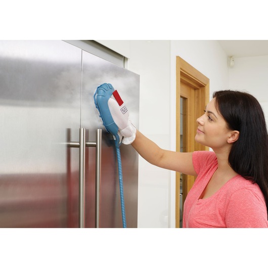 BLACK+DECKER FSMH13151SM steam cleaning mitt in use, cleaning stainless steel fridge door in modern kitchen.