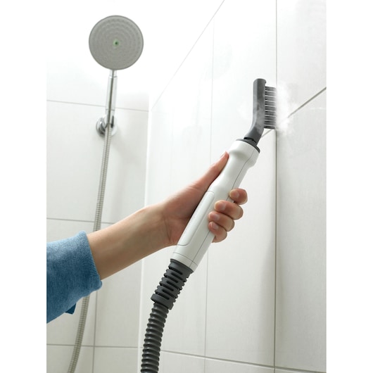 BLACKDECKER FSMH1351SM steam cleaner with brush attachment cleaning grout in bathroom tiles.