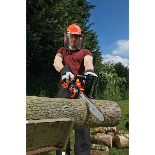 BLACKDECKER GKC3630L20 chainsaw cutting log outdoors, person wearing safety gear, product in use