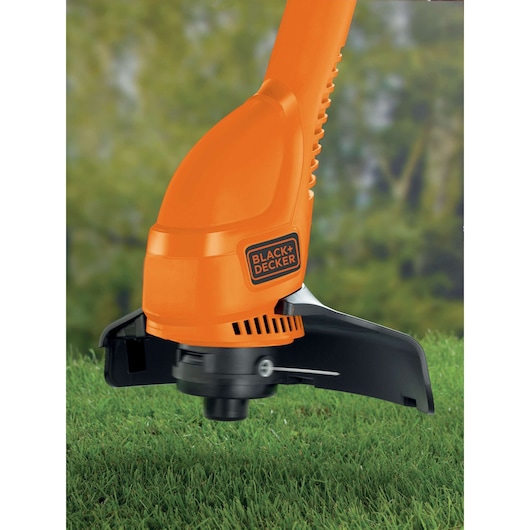BLACK+DECKER GL360 orange grass trimmer close-up on green lawn outdoors.