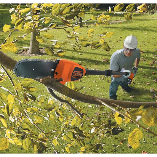 BLACK+DECKER GPC1820L20 cordless pole saw trimming tree branch outdoors.