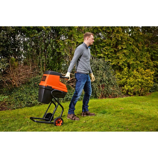 Photo of BLACKDECKER GS2400 garden shredder with orange and black body, being pulled by a person outdoors.