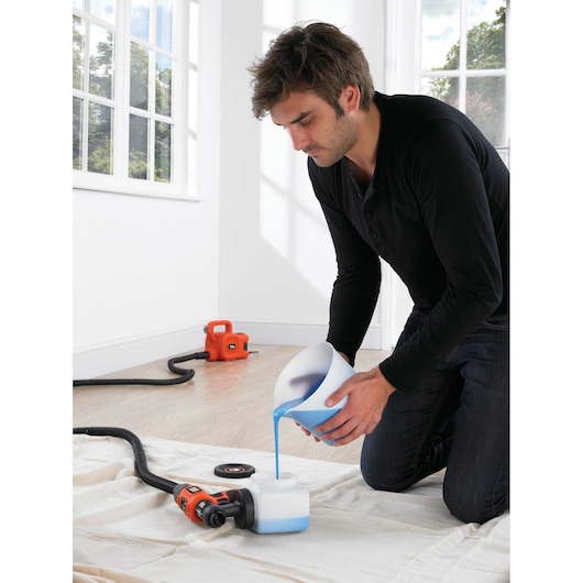 BLACKDECKER HVLP400 paint sprayer in use, blue paint being poured into container indoors.