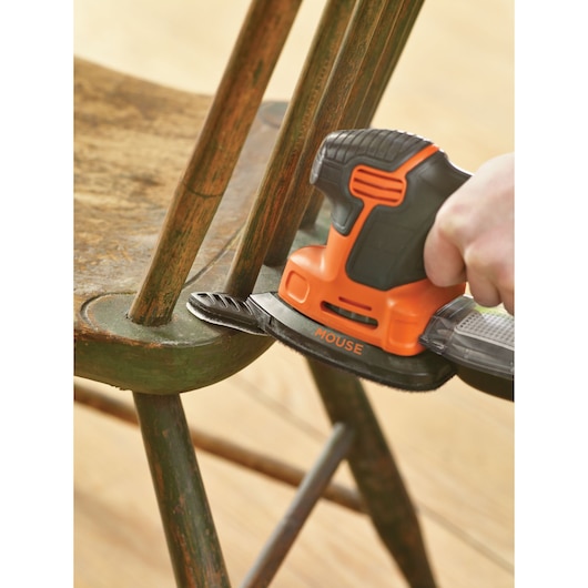 BLACKDECKER KA2000 mouse sander sanding a wooden chair, close-up angle.