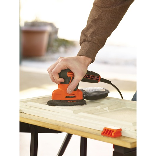 BLACKDECKER KA2000 mouse sander in use on wood surface, handheld, outdoor setting.