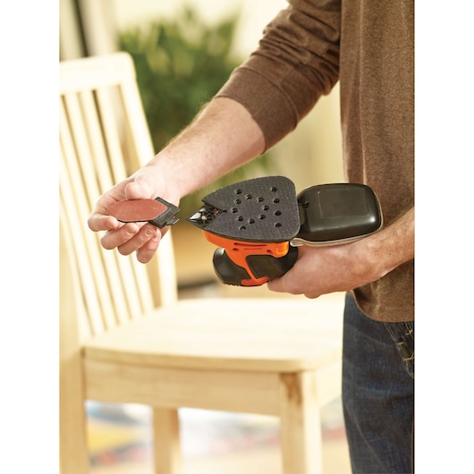Photo of BLACKDECKER KA2000 detail sander held in hand, with accessory being attached, indoor setting.