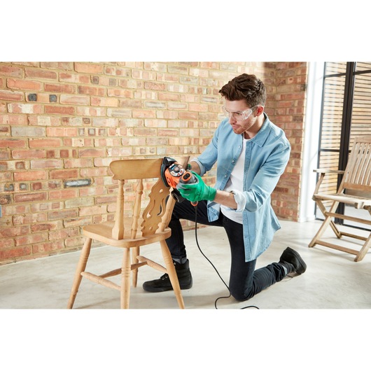 BLACKDECKER KA280 sander used on a wooden chair in workshop setting.