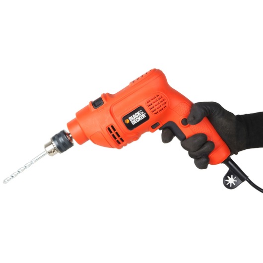 Photo of BLACKDECKER KR504RE-IN orange electric drill held in gloved hand, side view, with drill bit attached.