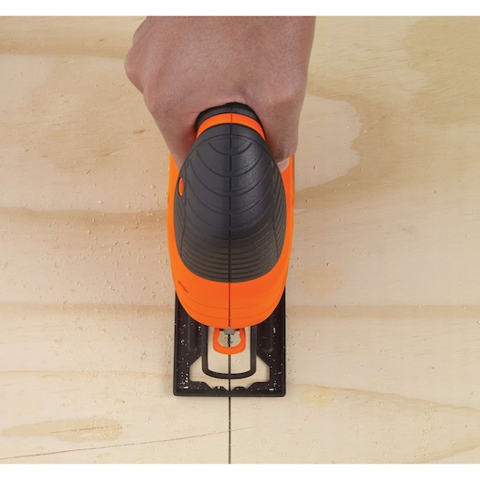Photo of BLACKDECKER KS701E jigsaw cutting straight line on plywood, top view showing handle and blade.
