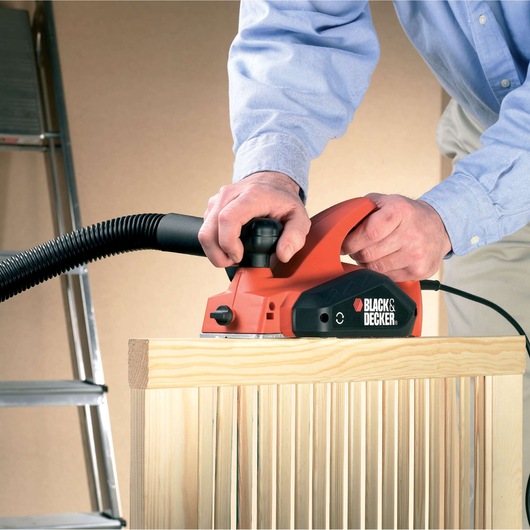 BLACKDECKER KW712KA electric planer being used on a wooden surface, hose attached, close-up view.