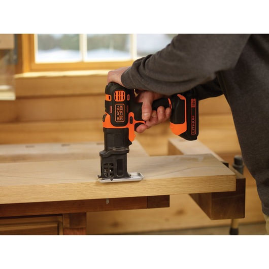 Photo of BLACK+DECKER MT218K cordless multi-tool cutting wood, shown in use on a workbench.