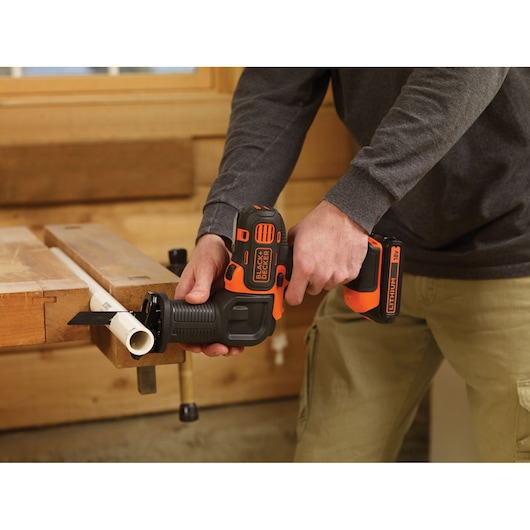 Photo of BLACKDECKER MT218K cordless reciprocating saw cutting a plastic pipe in a workshop setting.