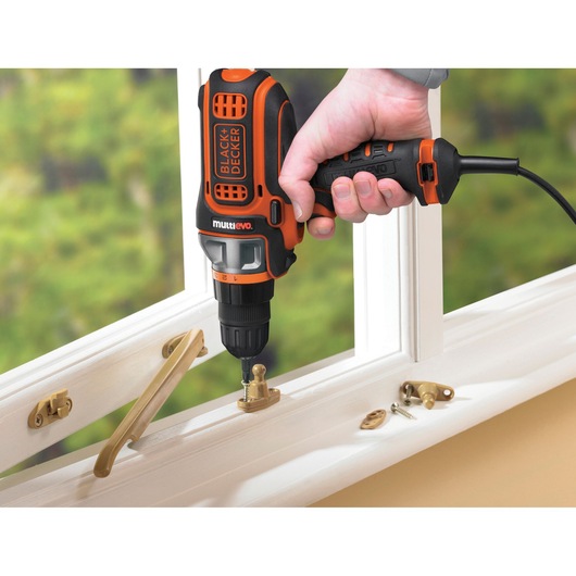 BLACKDECKER MultiEvo drill MT350k used to install brass hardware on white window frame.