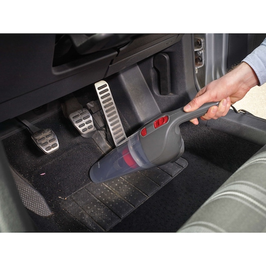 BLACKDECKER NV1210AV handheld vacuum cleaning car floor near pedals.