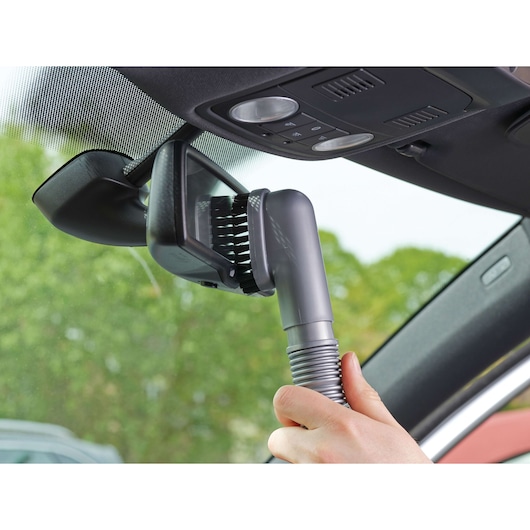 BLACKDECKER NV1210AV handheld vacuum cleaning car interior near mirror with brush attachment.