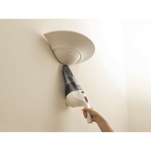 BLACKDECKER NV3610N handheld vacuum cleaning dust from a wall-mounted light fixture.